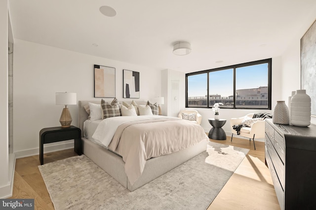 bedroom with expansive windows and light hardwood / wood-style flooring