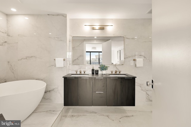 bathroom with a tub, vanity, and tile walls