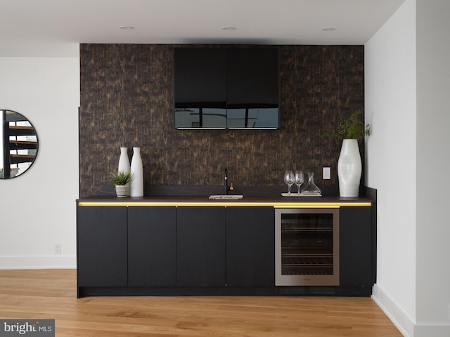 bar featuring beverage cooler, sink, and light hardwood / wood-style floors