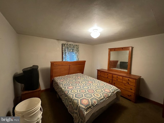 bedroom featuring dark carpet and a textured ceiling