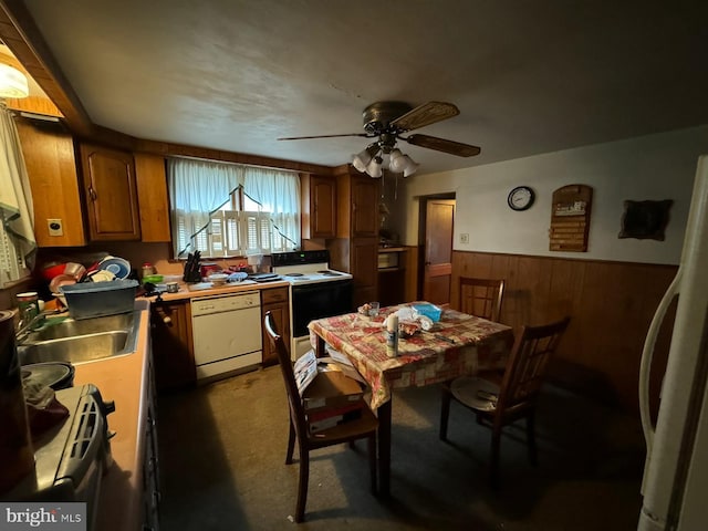 dining room with ceiling fan, wood walls, sink, and dark carpet