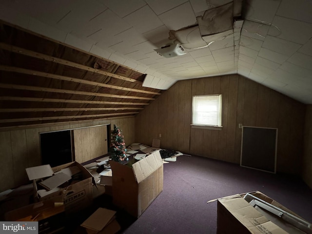 bonus room with dark colored carpet, lofted ceiling, and wood walls