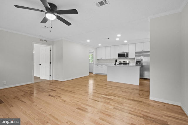 unfurnished living room featuring ceiling fan, ornamental molding, sink, and light wood-type flooring