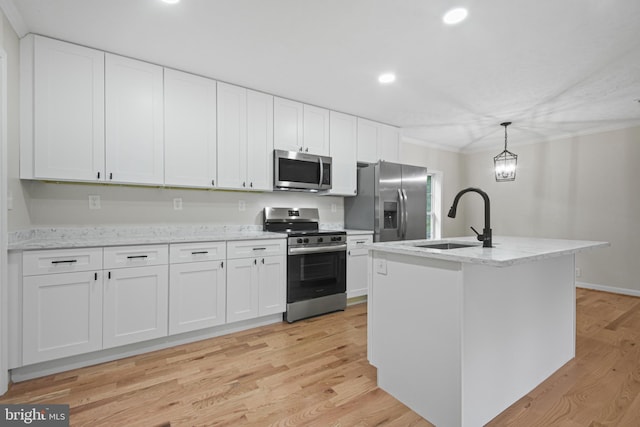 kitchen featuring appliances with stainless steel finishes, white cabinetry, a kitchen island with sink, light hardwood / wood-style flooring, and sink