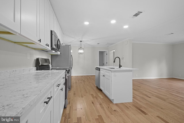 kitchen with white cabinets, appliances with stainless steel finishes, a kitchen island with sink, light hardwood / wood-style flooring, and sink