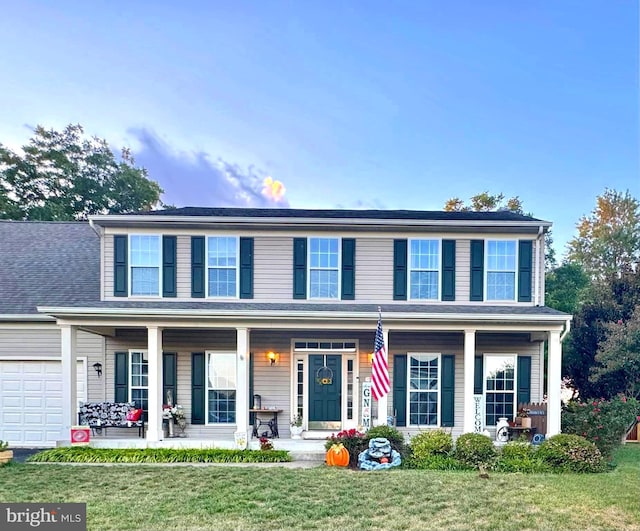 view of front of home featuring an attached garage, a porch, and a front yard