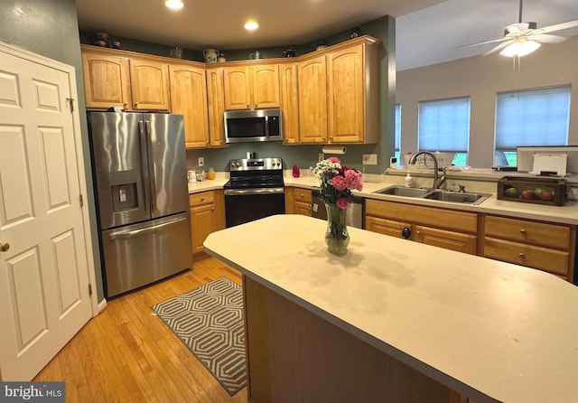 kitchen with ceiling fan, appliances with stainless steel finishes, light countertops, light wood-type flooring, and a sink