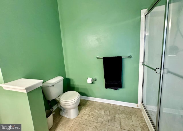 bathroom with toilet, a stall shower, and baseboards