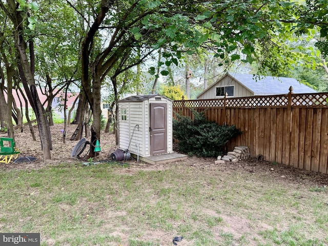 view of yard featuring a shed, an outdoor structure, and fence