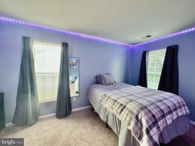 bedroom featuring baseboards, visible vents, and light colored carpet