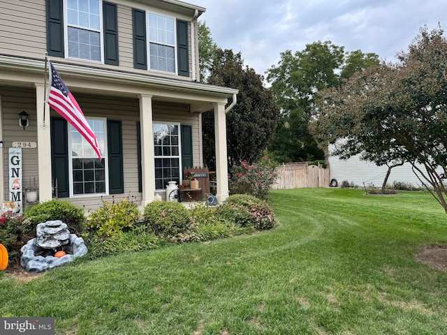 view of yard with covered porch and fence