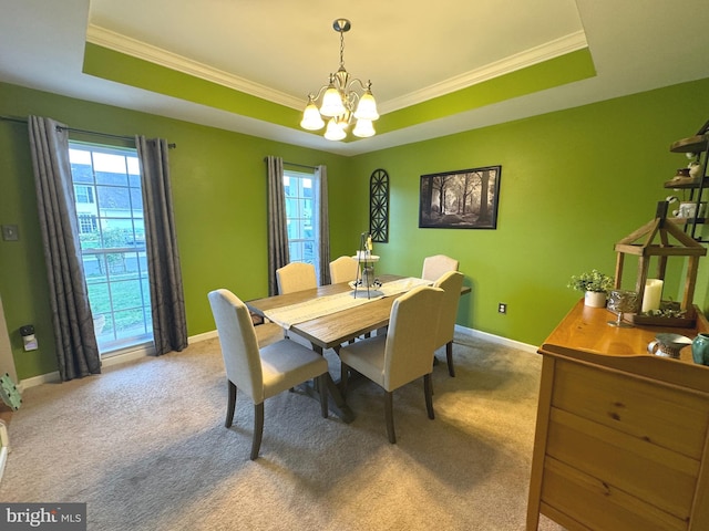 dining area with crown molding, a tray ceiling, light carpet, and a chandelier