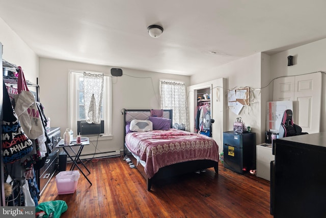 bedroom featuring baseboard heating and dark hardwood / wood-style floors