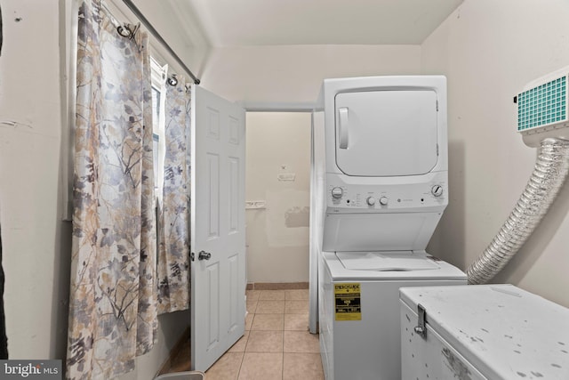 laundry area featuring stacked washing maching and dryer and light tile patterned floors