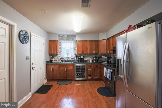 kitchen with wine cooler, dark wood-type flooring, sink, backsplash, and appliances with stainless steel finishes