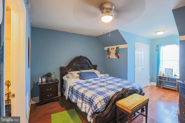 bedroom featuring ceiling fan, vaulted ceiling, a closet, and dark hardwood / wood-style flooring