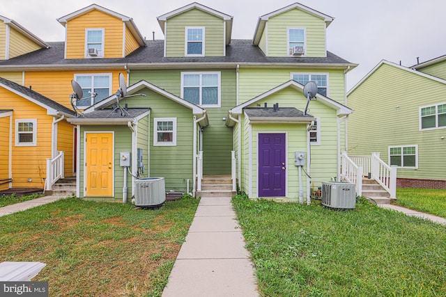 view of front of house with a front lawn and central AC