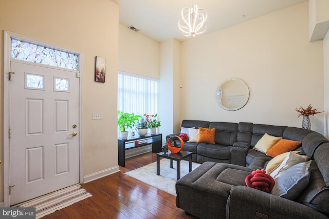 living room with a towering ceiling, dark hardwood / wood-style flooring, and a notable chandelier