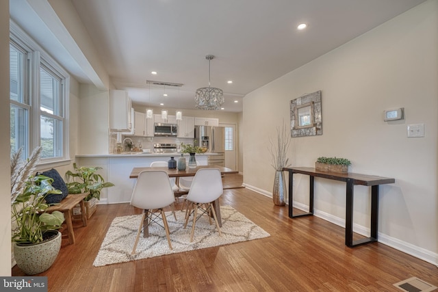 dining area with a notable chandelier and light wood-type flooring