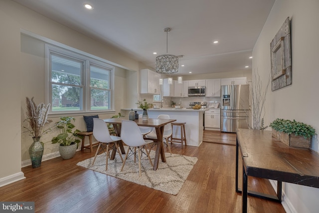 dining area with sink, hardwood / wood-style floors, and an inviting chandelier