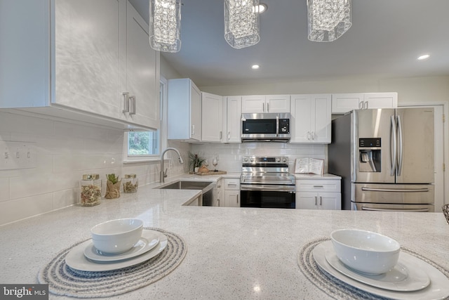 kitchen featuring light stone counters, stainless steel appliances, decorative light fixtures, and white cabinets