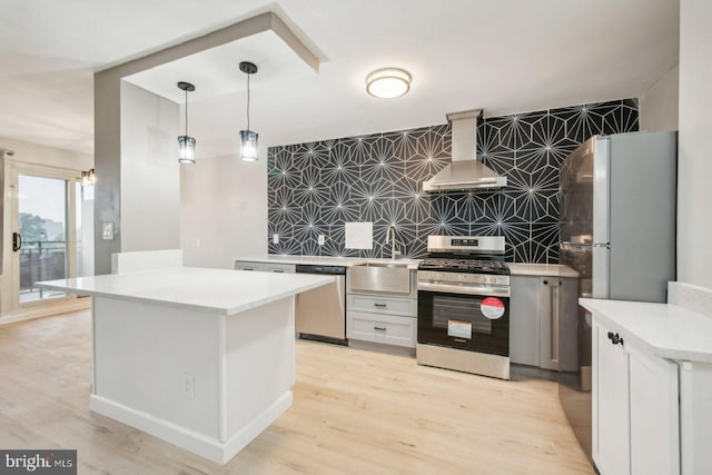 kitchen featuring light hardwood / wood-style flooring, appliances with stainless steel finishes, range hood, tile walls, and decorative backsplash