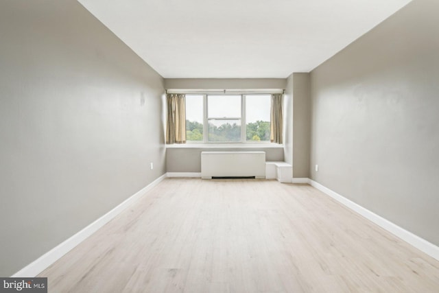 spare room featuring radiator heating unit and light hardwood / wood-style floors