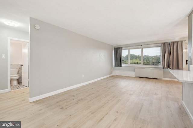 empty room featuring radiator heating unit and light hardwood / wood-style floors