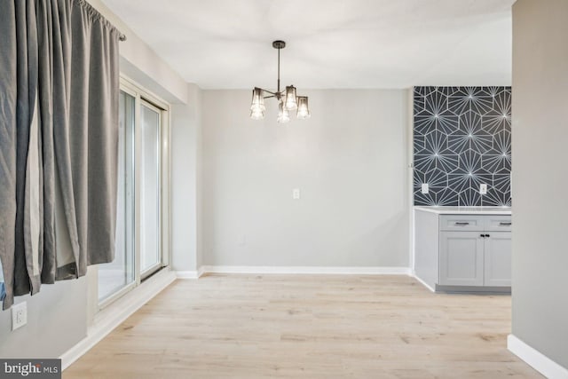 unfurnished dining area featuring a chandelier and light hardwood / wood-style floors