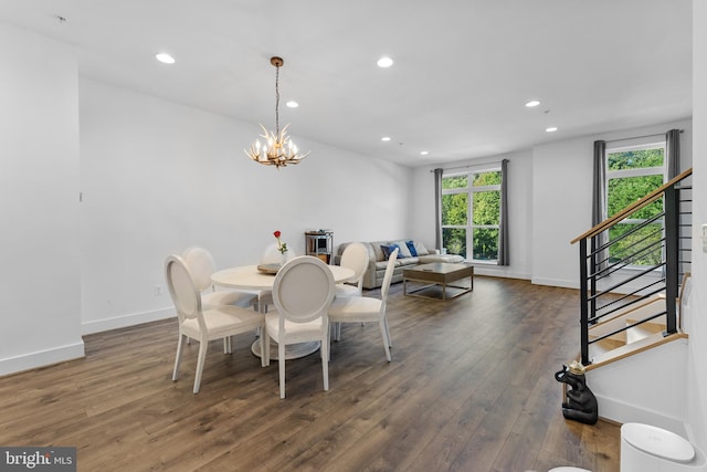 dining space featuring dark wood-type flooring and an inviting chandelier