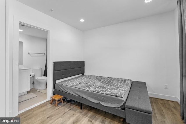 bedroom featuring light wood-type flooring and connected bathroom