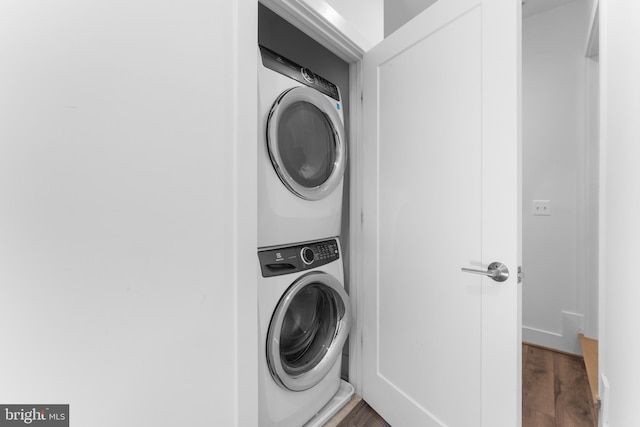 laundry area featuring stacked washer and clothes dryer and dark wood-type flooring