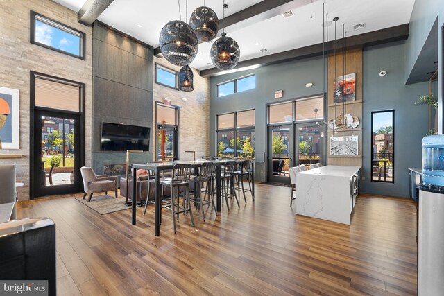 dining space featuring a high ceiling, beamed ceiling, plenty of natural light, and wood-type flooring