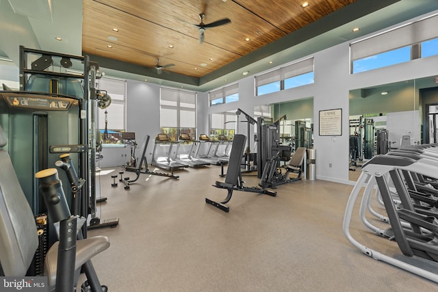 exercise room with a towering ceiling, wooden ceiling, and ceiling fan