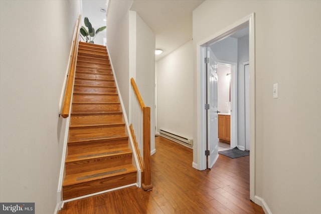 stairs featuring wood-type flooring and baseboard heating