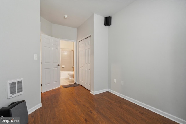 unfurnished bedroom featuring dark hardwood / wood-style floors, heating unit, and a closet