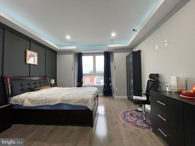 bedroom featuring light hardwood / wood-style floors and a raised ceiling