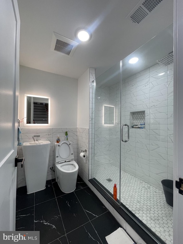 bathroom with tile walls, toilet, and a shower with door