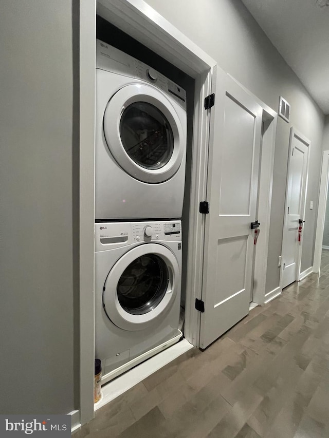 laundry area featuring stacked washer / dryer and hardwood / wood-style floors