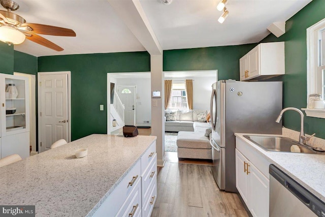 kitchen featuring ceiling fan, sink, white cabinetry, stainless steel appliances, and light hardwood / wood-style floors