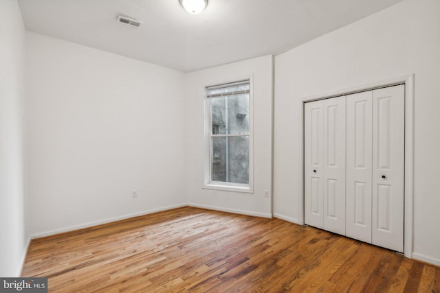 unfurnished bedroom featuring multiple windows, hardwood / wood-style floors, and a closet