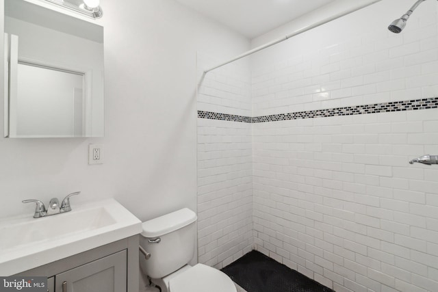 bathroom with vanity, toilet, and tiled shower