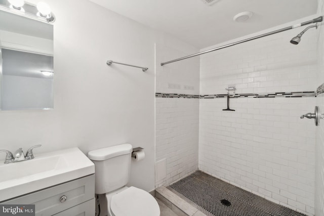 bathroom featuring tiled shower, vanity, and toilet