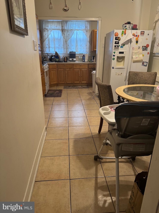 interior space featuring white fridge with ice dispenser and light tile patterned floors