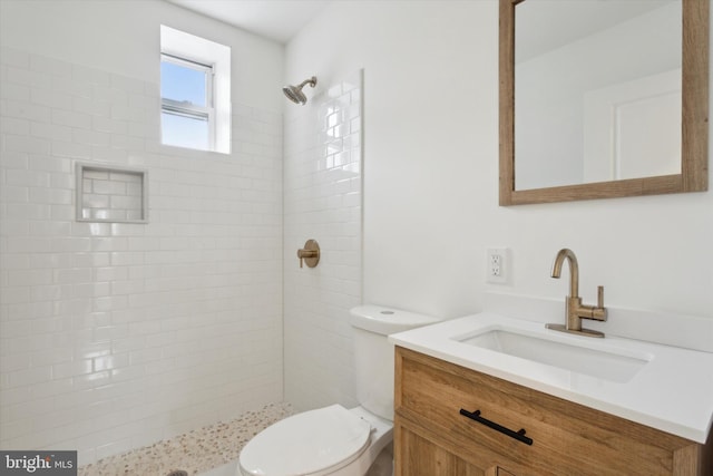 bathroom with vanity, toilet, and tiled shower