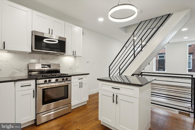 kitchen with appliances with stainless steel finishes, hanging light fixtures, and white cabinetry