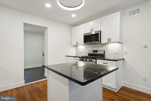 kitchen featuring white cabinets, a kitchen island, decorative backsplash, appliances with stainless steel finishes, and dark hardwood / wood-style flooring