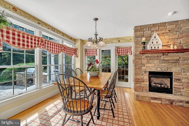 dining room featuring a stone fireplace and light hardwood / wood-style flooring