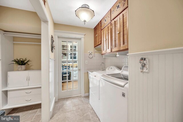 clothes washing area with washer and dryer and cabinets