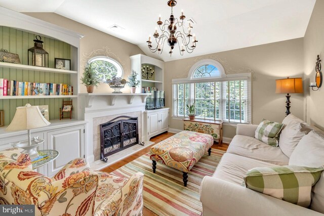 living room featuring lofted ceiling, a chandelier, and light hardwood / wood-style floors